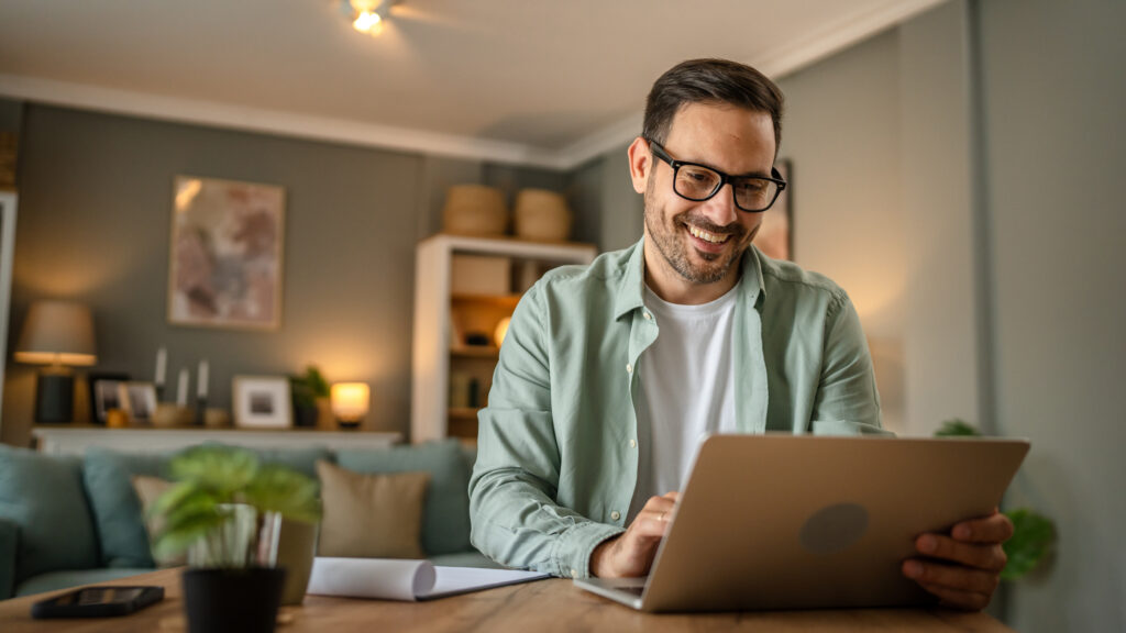 one male with beard work on his laptop computer at home happy smile success freelance entrepreneur or remote work concept