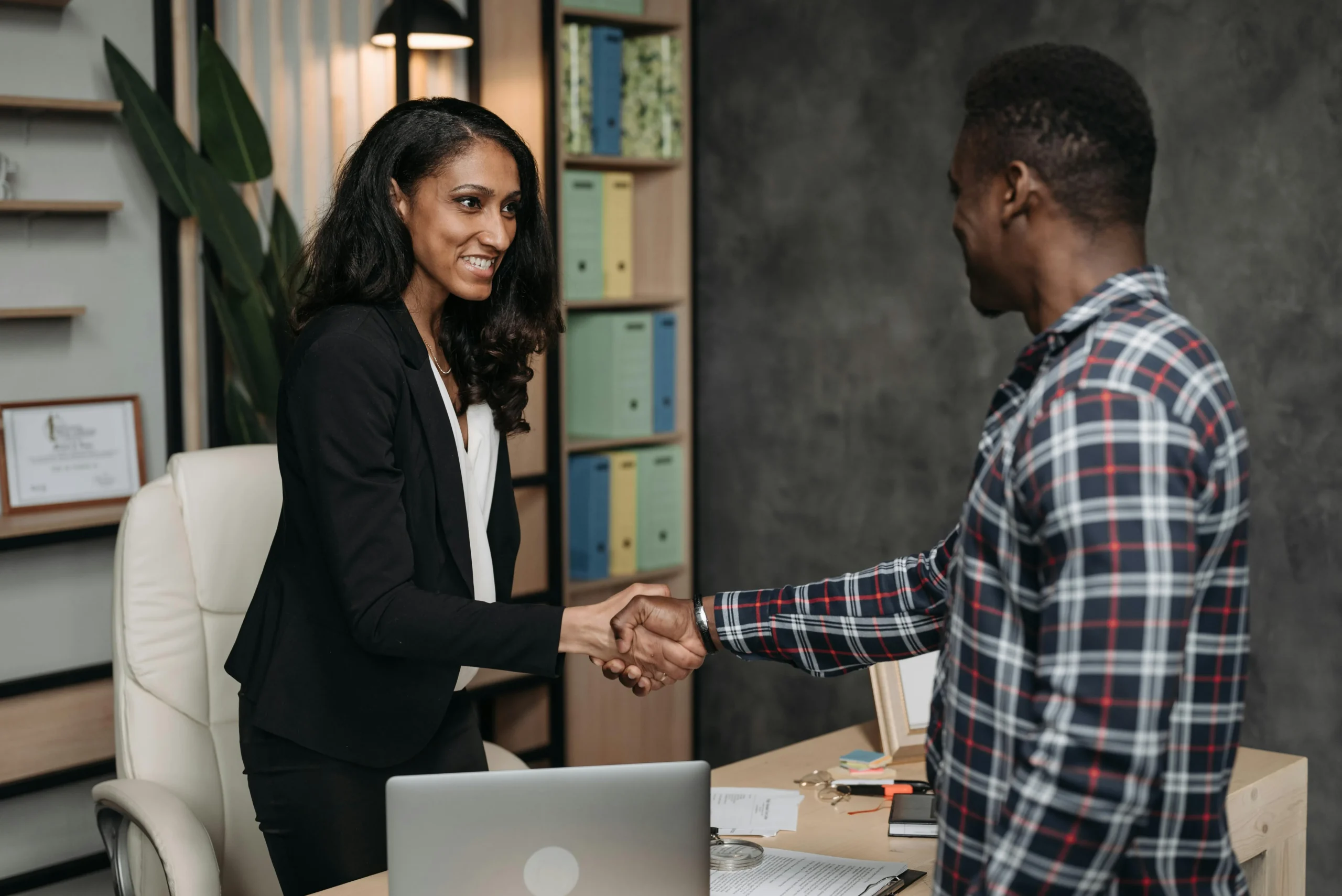 Male and female colleagues shaking hands over a desk