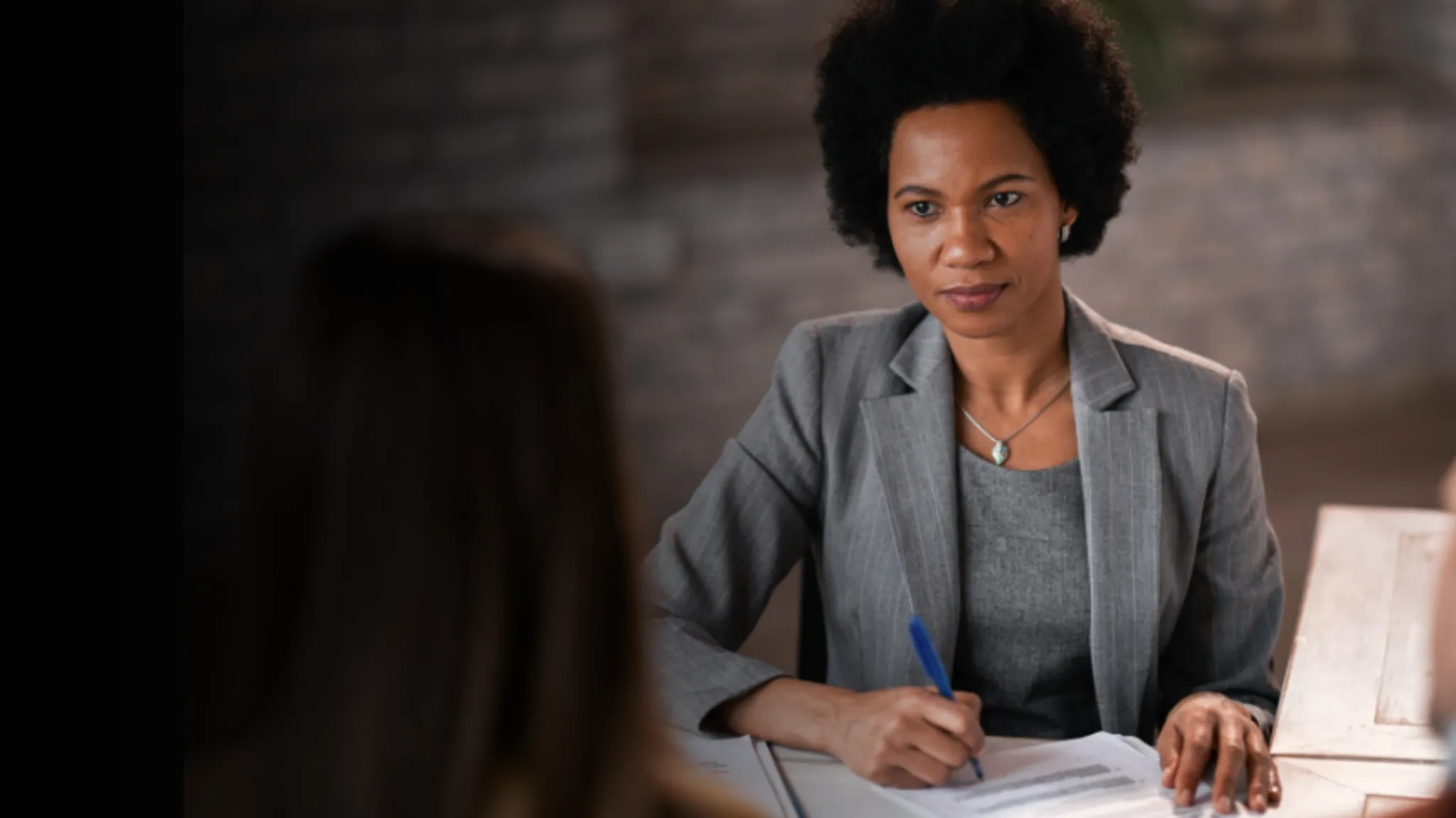 Professional woman making notes while speaking to a client
