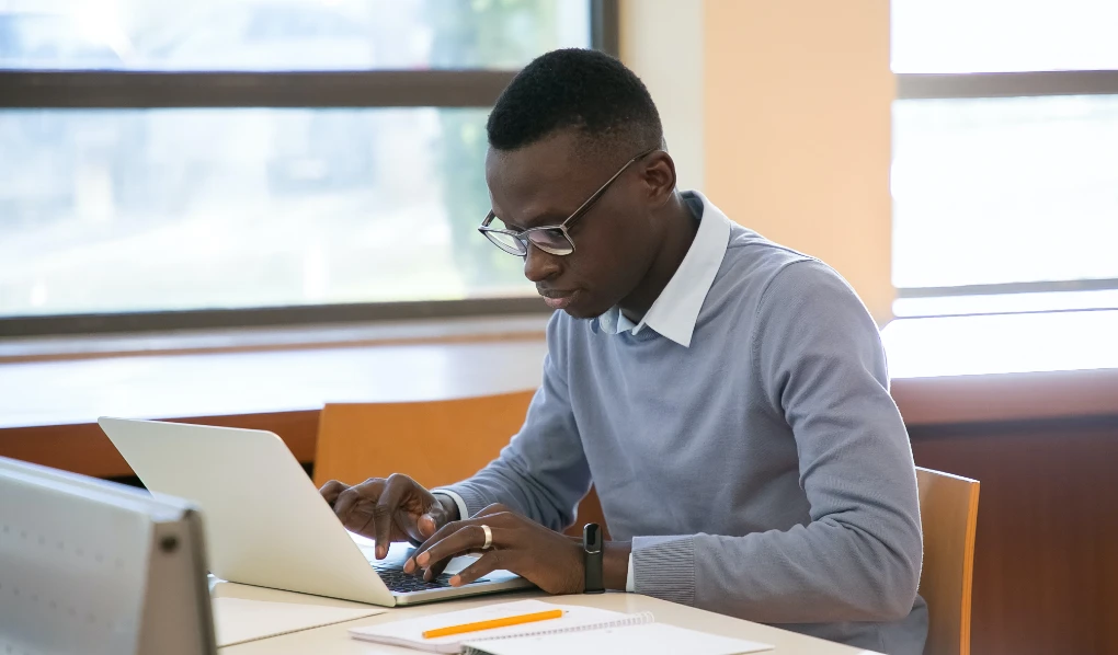 Male student typing on laptop