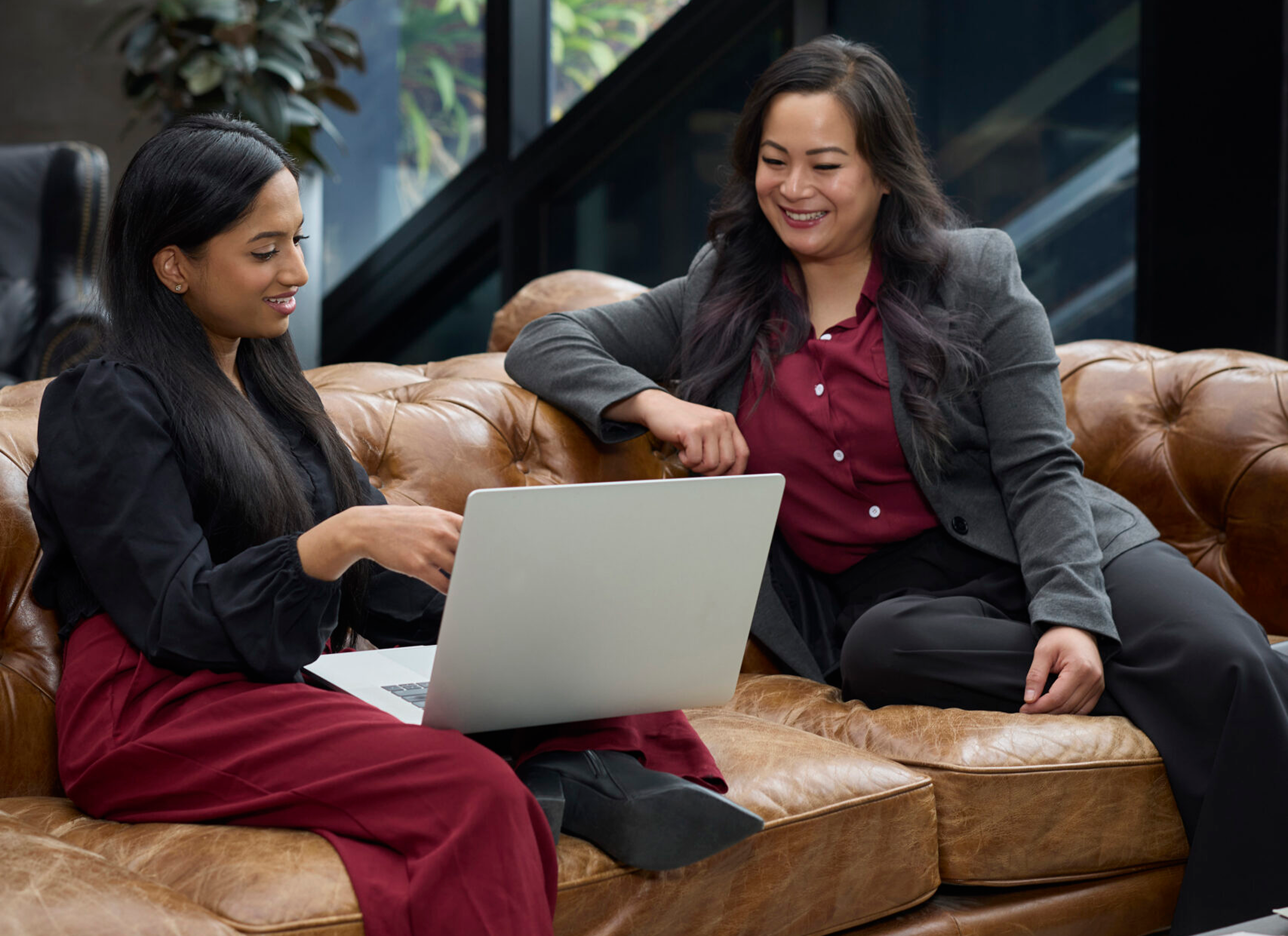 Two professional women studying on the couch.