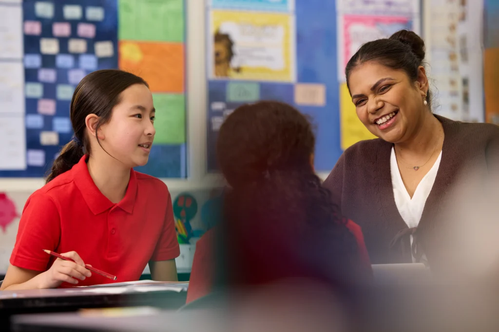 What skills do primary teachers need for today’s diverse classrooms - a primary school teacher having an in-depth discussion with two of her students in a classroom.